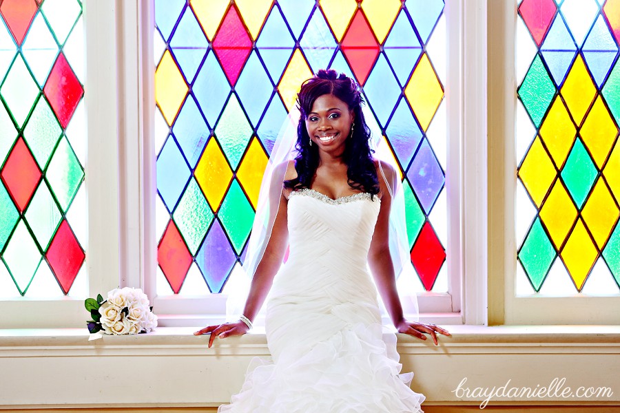 white bouquet medium veil bride sitting by stained glass window by Bray Danielle Photography
