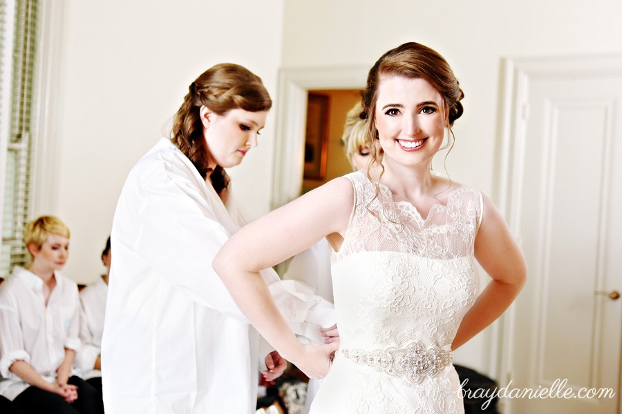 bridesmaid helping lace up wedding gown