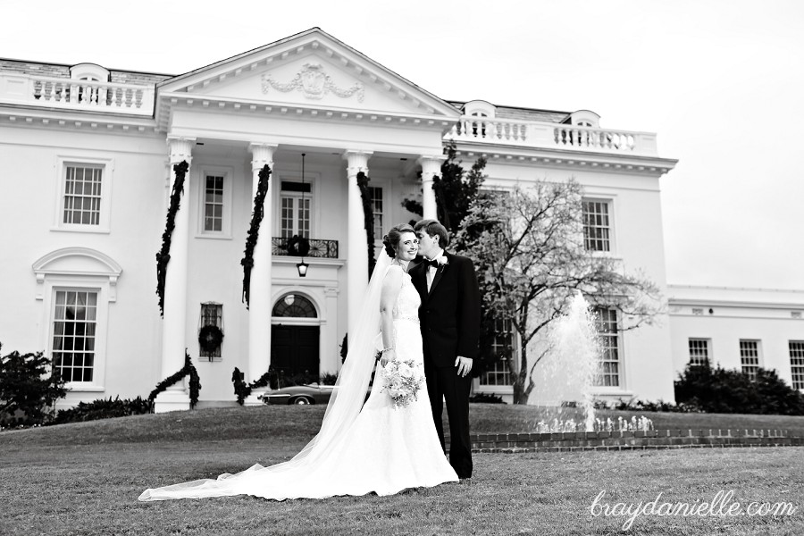 bride and groom in front of mansion