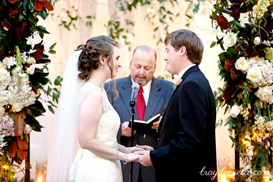 bride and groom under flower arch