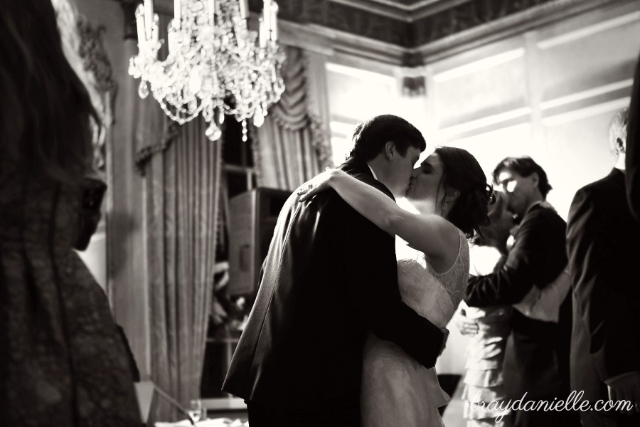 bride and groom kissing under chandelier