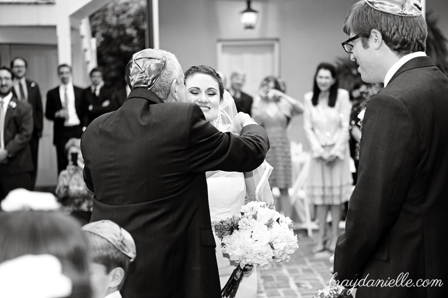 Father of the bride kissing bride on the cheek