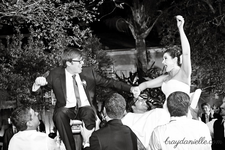 Bride and groom being lifted on chairs