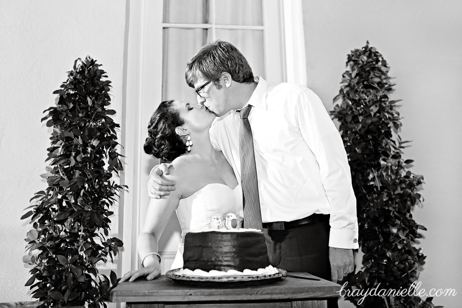 bride and groom kissing by cake