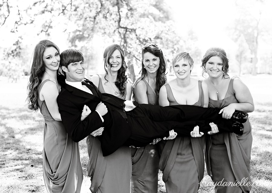 Bridesmaids holding groom up