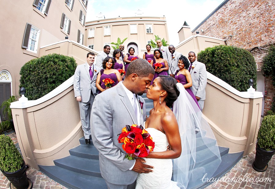 Bride and groom kissing with wedding party in background