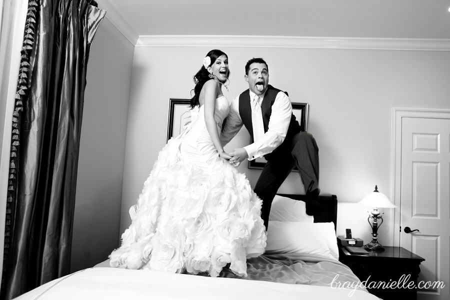 Bride and groom jumping on bed